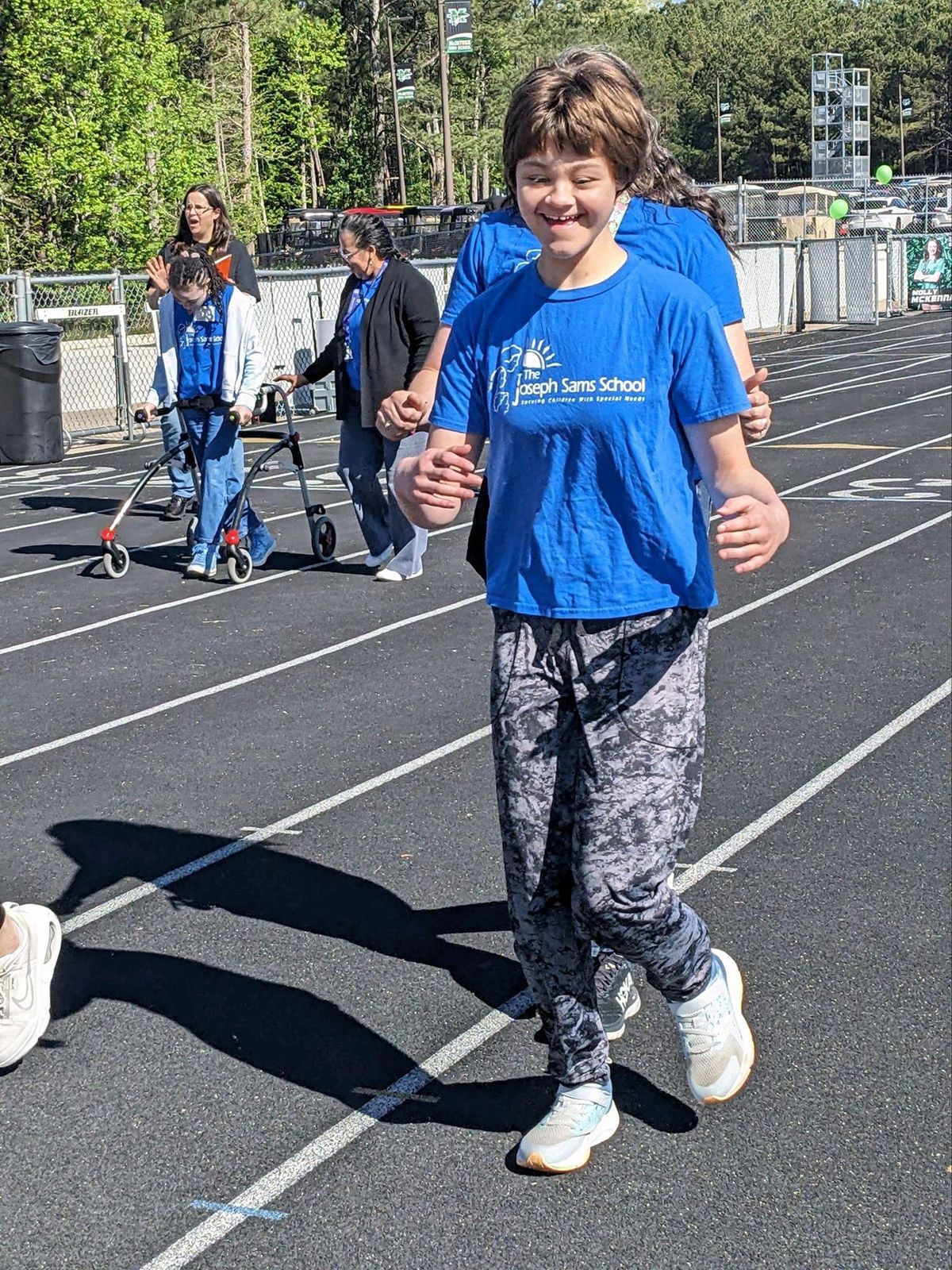 Abby smiling as she walks a track on a bright spring day.